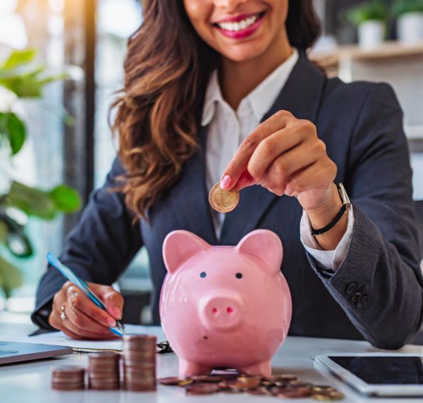 Businesswoman with piggy bank on desk (Adobe AI)